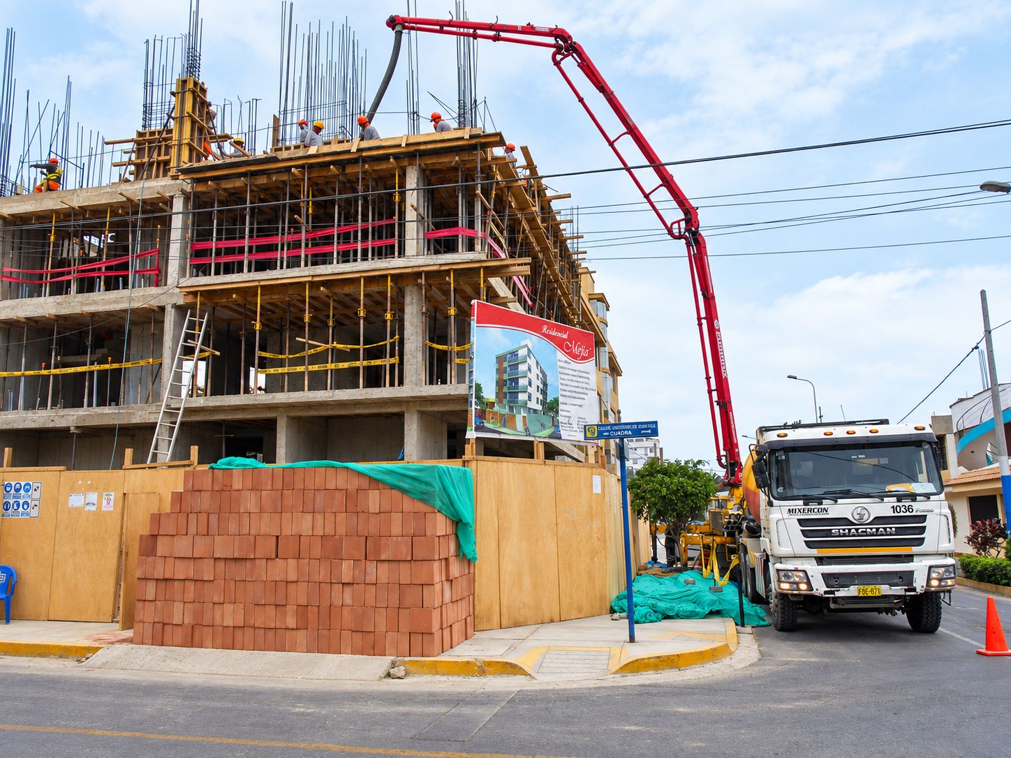 Edificio de varios niveles en construcción, con encofrados y una bomba de concreto trabajando desde la calle.